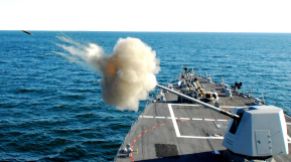 A Mk-45 Mod.4 naval gun fires a shell during a live-fire exercise. This gun can fire 20 rounds per min.